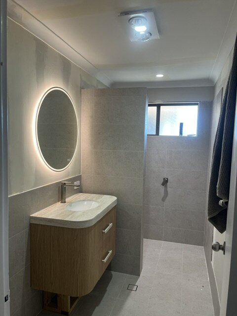 Finished bathroom with illuminated round mirror and downlights